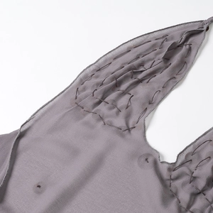 Dettaglio del tessuto grigio a balze con arricciature testurizzate e cuciture del vestito