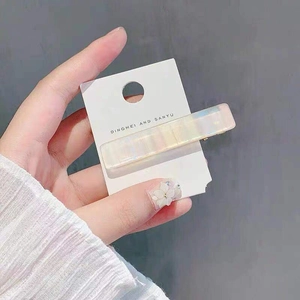 Macro view of rectangular iridescent pearl resin hair clip on white display card