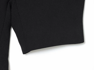 Close-up of black woven fabric texture showing detailed granular weave on the dress cuff