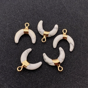 Close-up of crescent-shaped white marble stone pendants with gold bails for DIY jewelry