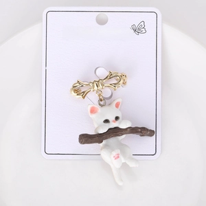 Detail of a white cat climbing a brown branch brooch with a golden bow on jewelry card
