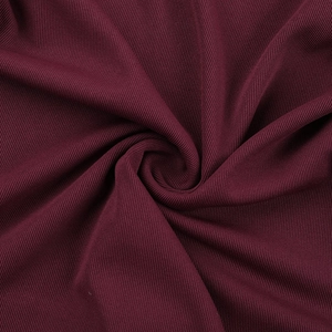 Macro detail of burgundy ribbed knit fabric showing rich vertical texture and quality