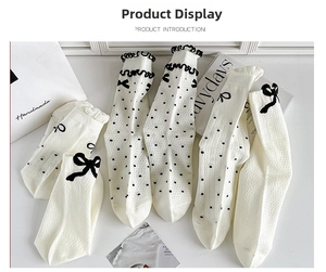 Detail of white cotton crew socks with polka dots, bows, and ruffled edges in a soft style