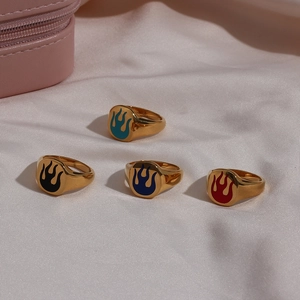 Detail of four gold-plated signet rings with colorful flame patterns on white silk fabric