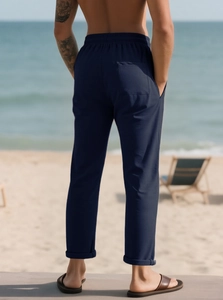 Vista posteriore dettagliata dei pantaloni casual blu scuro con elastico in vita in spiaggia