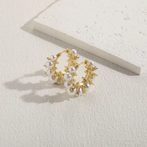 Close-up of elegant gold plated hoop earrings with white pearls and sparkling cubic zirconia