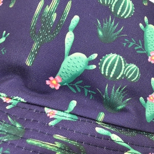 Détail du tissu violet avec motif de cactus et coutures de précision sur le chapeau
