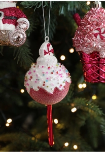 Close-up of pink glitter Christmas ornament with a festive bow hanging on a tree