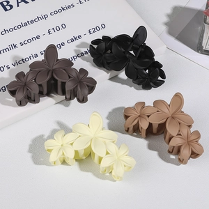 Detailed view of matte flower hair claws in black, brown, and cream colors for women