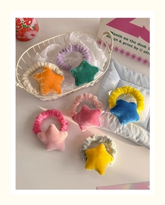 Flat lay of colorful plush star hair ties in soft velvet material on cozy Ins-style background