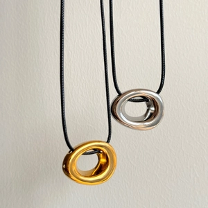 Vertical view of fluid metallic circle pendants in gold and silver with black cords