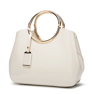 Fashionable cream patent leather handbag with round metal handles and crossbody strap