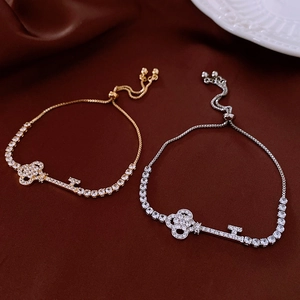 Detail of adjustable zircon key charm bracelet with gold and silver finishes on silk