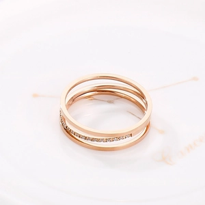 Macro shot of rose gold triple-layer steel ring with inlaid cubic zirconia in a dish
