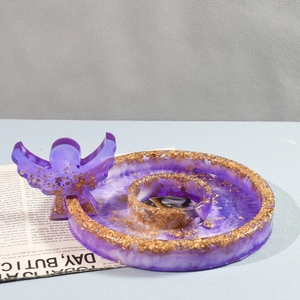 Detail of purple translucent resin angel figurine and round tray with gold foil flakes