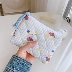 Détail d'une trousse matelassée en coton avec motifs lapins et pompon bleu tissé
