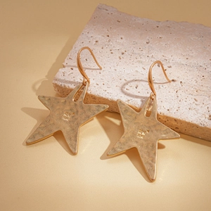 Detail shot of gold star-shaped earrings with 925 silver hallmark on stone background