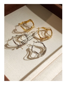 Detailed view of wavy geometric hoop earrings in polished gold and silver finishes