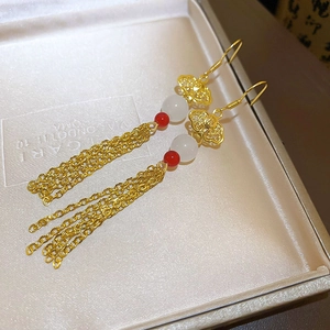 Detail of gold tassel earrings with cloud pattern and jade beads in a jewelry box