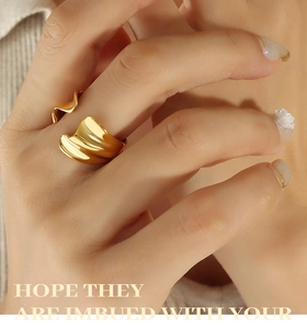 Close-up of golden wavy irregular ring on finger with polished mirror metallic finish