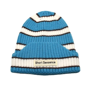 Close-up of blue and white striped knit beanie featuring a Short Sensence woven label
