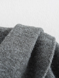 Dettaglio del tessuto del poncho in maglia grigia che mostra la trama morbida e le fibre