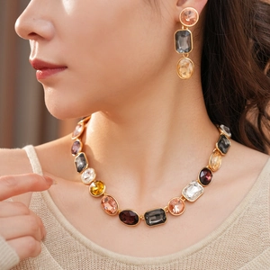 Dettaglio di un set vintage dorato con collana e orecchini con gemme colorate miste