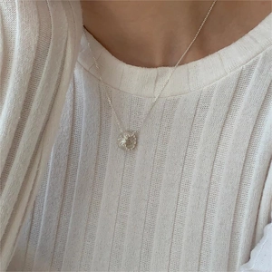 Detail of s925 sterling silver necklace with textured circular pendant on model