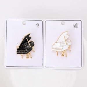 Detail view of black and white enamel piano brooches on display cards showing alloy texture