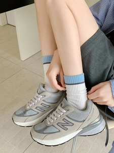 Détail de baskets en daim gris et bleu clair avec logo N et marquage du modèle 990