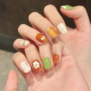 Short round floral press-on nails in orange, green, and white with 3D flower and pearl decor