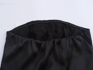 Nahaufnahme des schwarzen Satin-Bandeau-Tops mit feiner weißer Spitzenborte am Ausschnitt