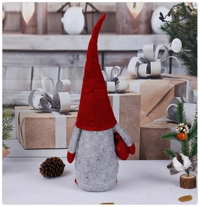 Close-up of a Nordic Christmas gnome doll with pinecones and gift boxes on a wooden table