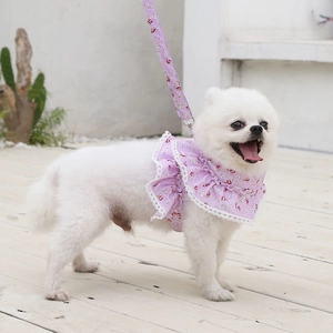 Close-up of floral pet harness with lace trim and metal D-ring on light wood floor