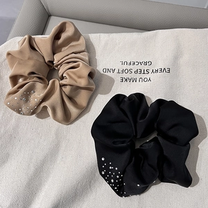 Close-up of beige and black velvet scrunchies with sparkling rhinestone accents on canvas
