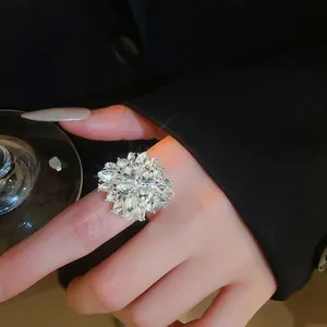 Elegant floral cluster ring with marquise rhinestones on hand holding glass