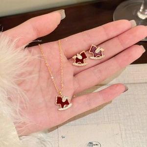 Detailed view of 18K gold plated necklace and earrings with red enamel horse charms