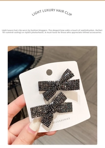 Detail view of two luxury black rhinestone bow hair clips on a white display card