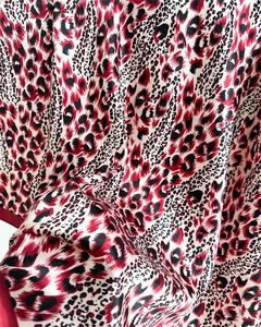 Detailed close-up of soft satin fabric with a classic red and black leopard print pattern