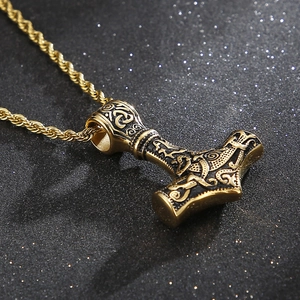 Close-up of golden Mjolnir pendant with viking carvings and twisted chain necklace
