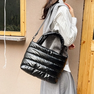 Chic black quilted puffer tote bag with detachable strap shown in lifestyle setting
