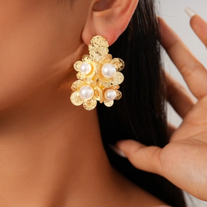 Detail of 18K gold-plated flower earrings with pearls worn by a model in soft lighting