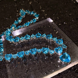 Close-up of heart-shaped topaz blue sapphire zircons in silver prong setting necklace