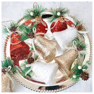 Gros plan de cloches de Noël pailletées avec aiguilles de pin et pommes de pin sur plateau
