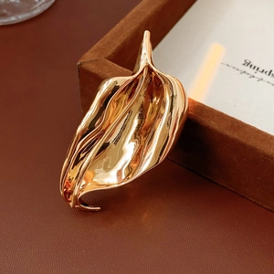 Detailed view of irregular golden leaf brooch with polished finish and flowing design
