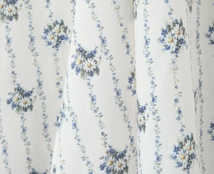 Close-up of white textile fabric with delicate blue floral print and vine stripes