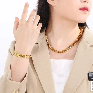 Close-up of golden 10mm Miami Cuban link necklace and bracelet set worn by model