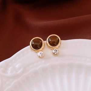 Macro shot of retro brown resin stud earrings with gold plating and sparkling crystals