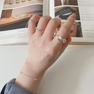 Close-up of 925 sterling silver twisted rope ring and thin heart bracelet on hand