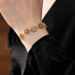 Close-up of a vintage golden daisy bracelet featuring olive green zircon flower petals